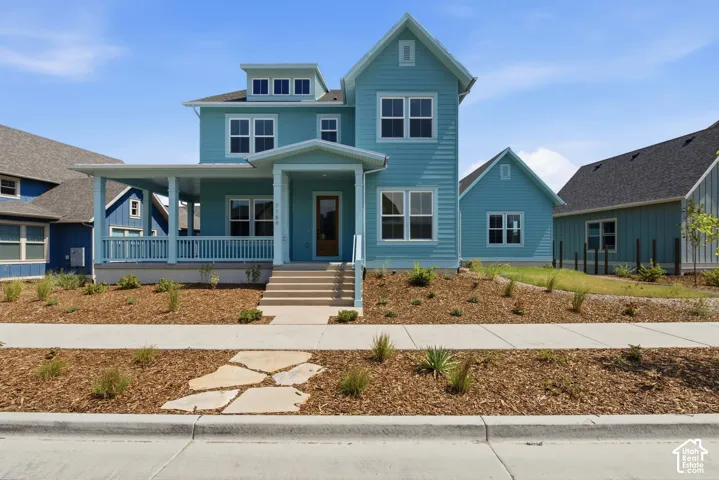 Two-story residence featuring light blue siding, a covered front porch, and a dormer window