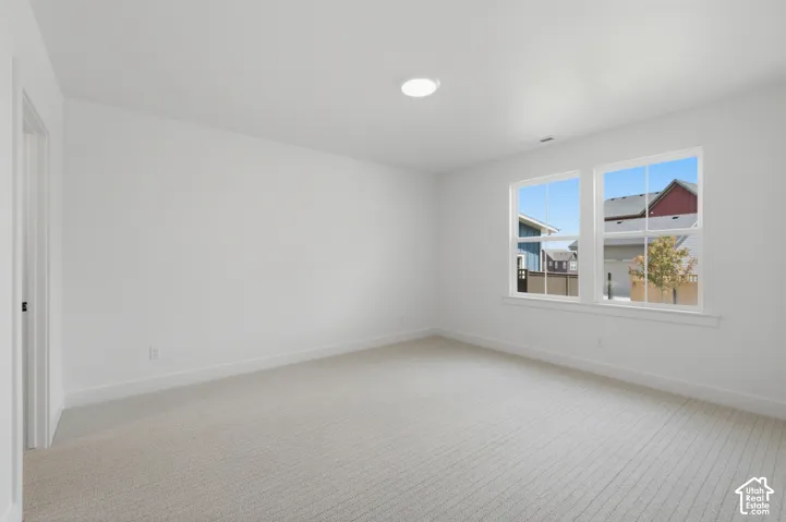 Recessed ceiling lighting, light-toned carpeting, white walls, white trim, and a window with white casing