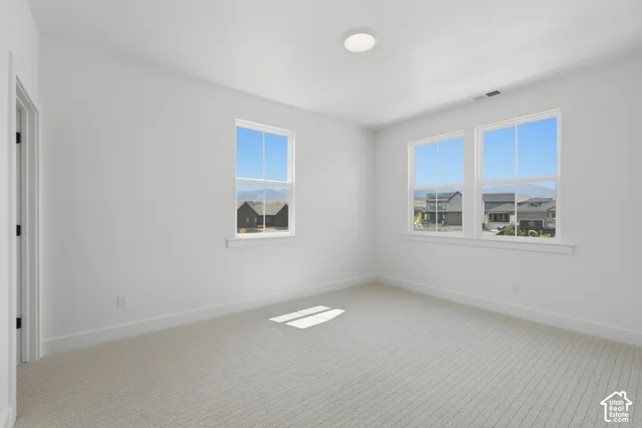 Bright corner bedroom flooded with natural light through two large windows showcasing scenic landscape views