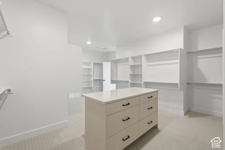 Walk-in closet featuring a center island with drawers, white countertop, and built-in shelving