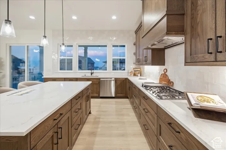 Kitchen featuring wood cabinetry, quartz countertops, a large center island, tile backsplash, and stainless steel appliances