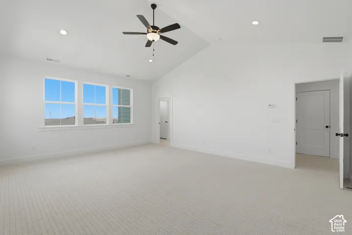 Vaulted ceiling with recessed lighting, ceiling fan, triple windows, and neutral carpeting