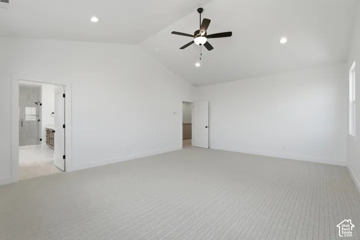 Vaulted ceiling with a ceiling fan, recessed lighting, carpet flooring, window, and an en-suite bathroom with a glass shower enclosure