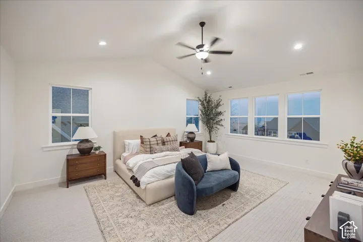 Primary Suite! Vaulted ceilings featuring recessed lighting and a central ceiling fan, complemented by neutral wall-to-wall carpeting and abundant natural light from multiple double-hung windows
