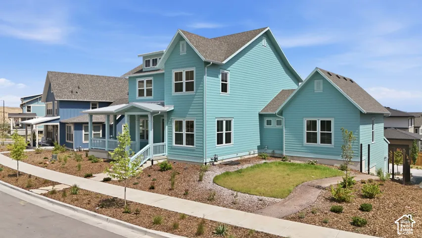 Contemporary exterior with light blue siding, multiple gables, white trim windows, and a covered front porch