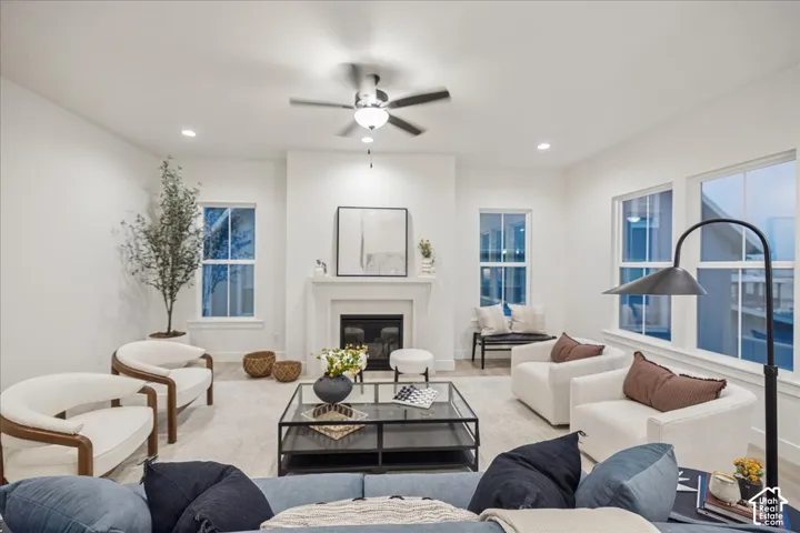 Fireplace with a classic surround, recessed ceiling lighting, multi-blade ceiling fan, and large windows with paneled detailing