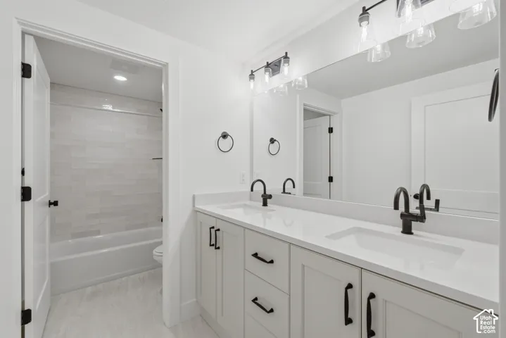 Spa-inspired primary bathroom featuring dual vanities with white quartz countertops, white cabinetry with matte black hardware, and matte black faucets