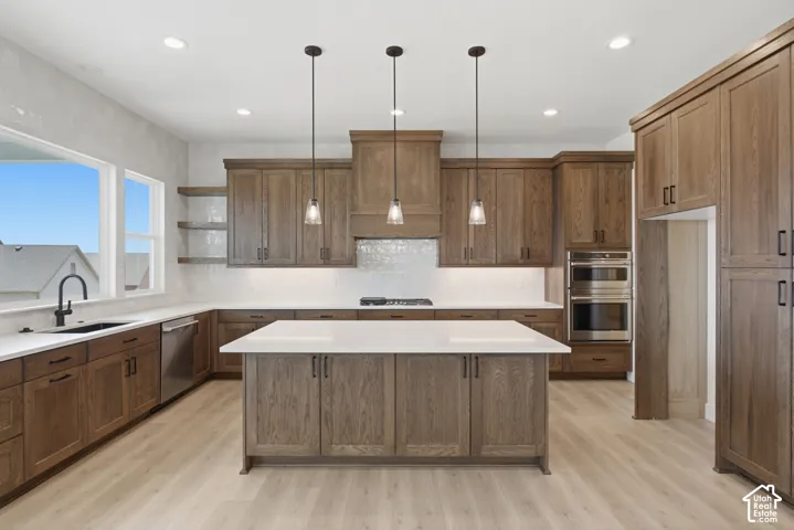 Kitchen featuring wood-finish cabinetry, a central island with white countertops, stainless steel double ovens, and a black faucet