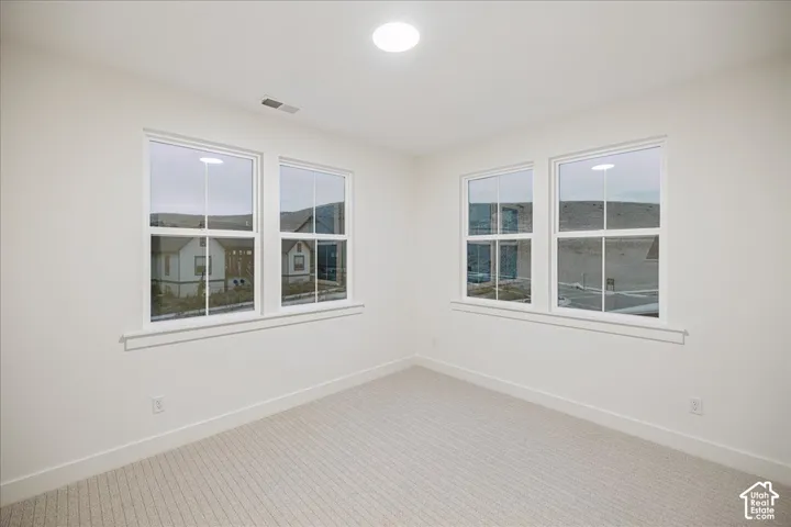 Neutral-toned wall-to-wall carpeting, dual-pane windows with grid detailing, and a circular recessed ceiling light