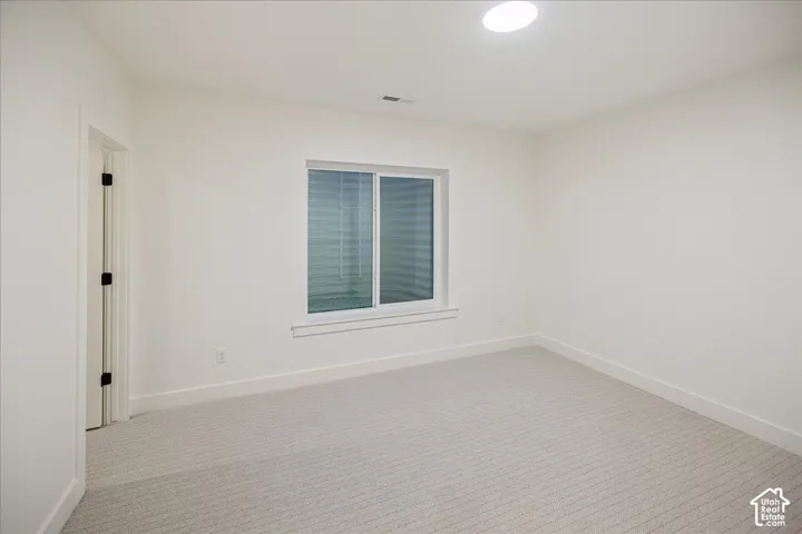 Neutral-toned carpeting, white walls, sliding window with a window well, and recessed lighting