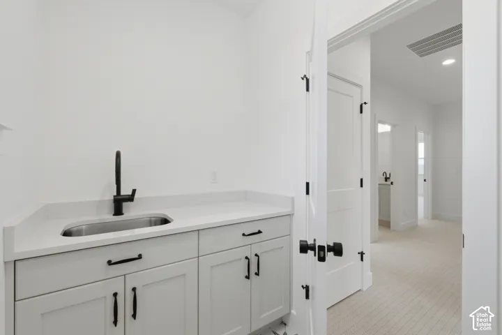 White shaker cabinetry with matte black hardware, stainless steel sink, black gooseneck faucet, and light-toned countertop