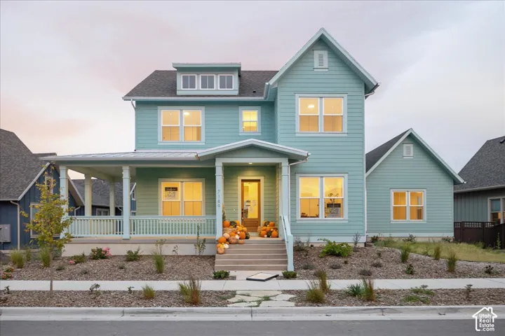 Two-story residence featuring lap siding, a covered front porch with a gabled roofline, a dormer window, and stone landscaping
