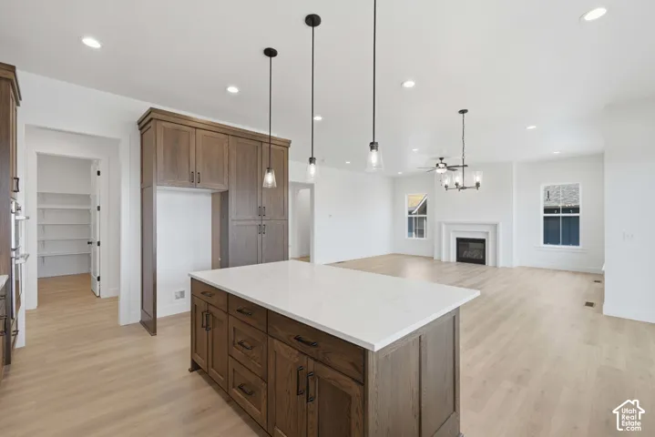 Spacious kitchen featuring an island with a light-toned countertop, wood-finish cabinetry, and recessed lighting