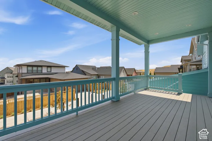 Expansive covered balcony featuring a composite deck surface, decorative railing, and recessed ceiling lighting