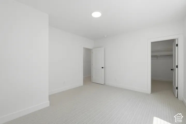 Neutral wall paint, recessed ceiling light, white paneled doors, black door hardware, and patterned carpet flooring