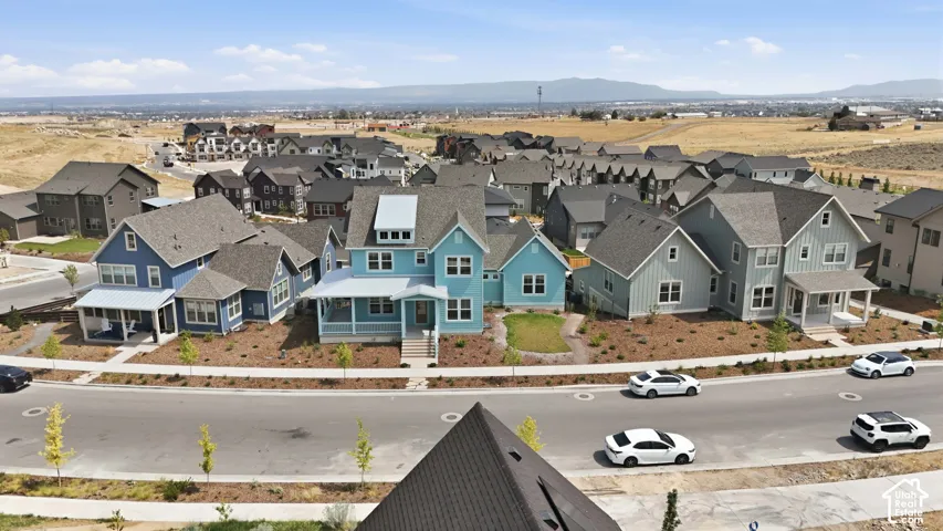 Residential area featuring multiple houses with varied siding colors and rooflines, established street, and expansive undeveloped landscape