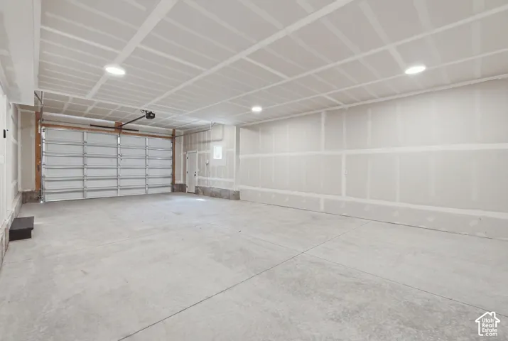 Spacious unfinished garage with a concrete floor, recessed ceiling lighting, and an overhead garage door