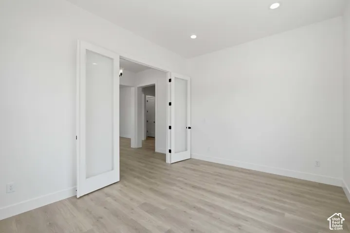 Light wood-finish flooring, recessed ceiling lighting, and crisp white walls