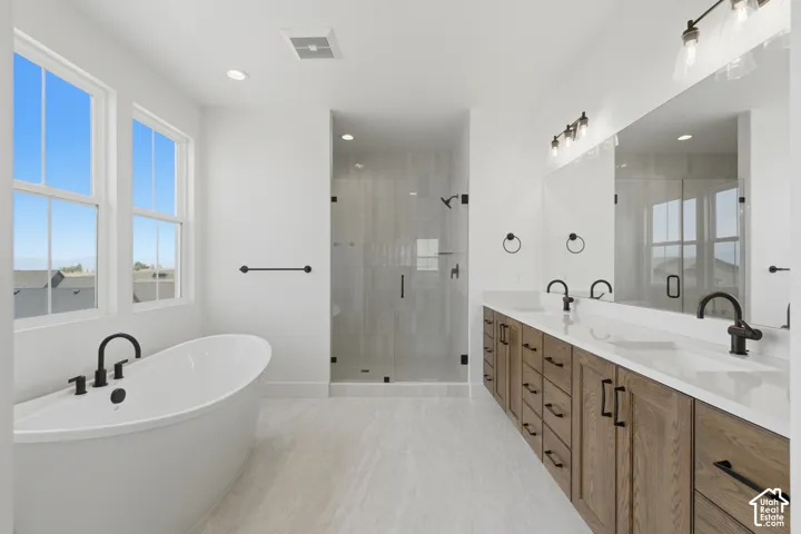 Freestanding soaking tub, dual windows, glass-enclosed shower, dual vanity with undermount sinks, and plank-style flooring