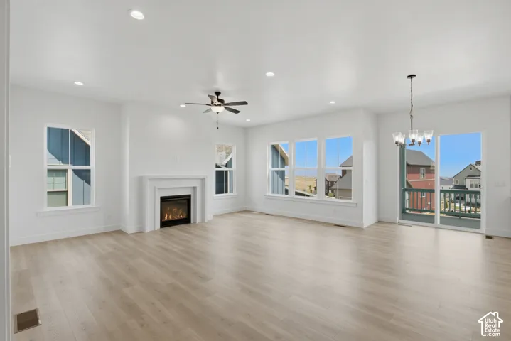 Spacious open-concept room featuring light wood-finish flooring, a contemporary fireplace with a white mantel, and multiple windows