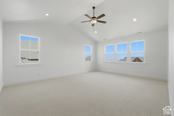 Primary Suite Vaulted ceiling, recessed lighting, ceiling fan, multiple windows, and light-toned carpeting