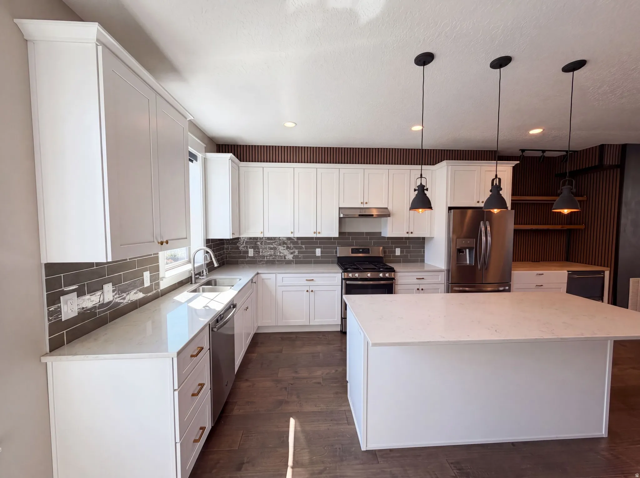 White cabinetry, stainless steel appliances, wood-finish flooring, island with countertop, and dark subway tile backsplash