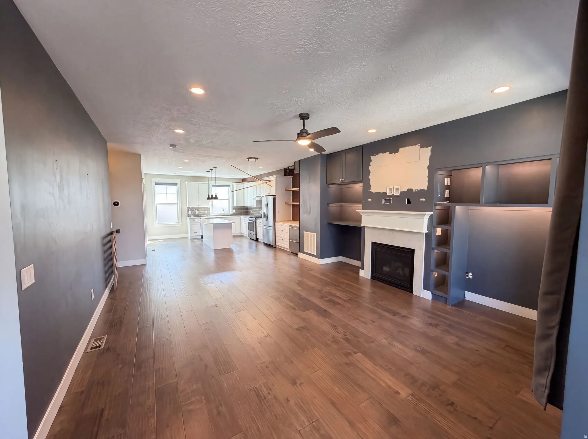 Wood-finish flooring throughout, recessed lighting, ceiling fan, fireplace with mantel, and built-in shelving