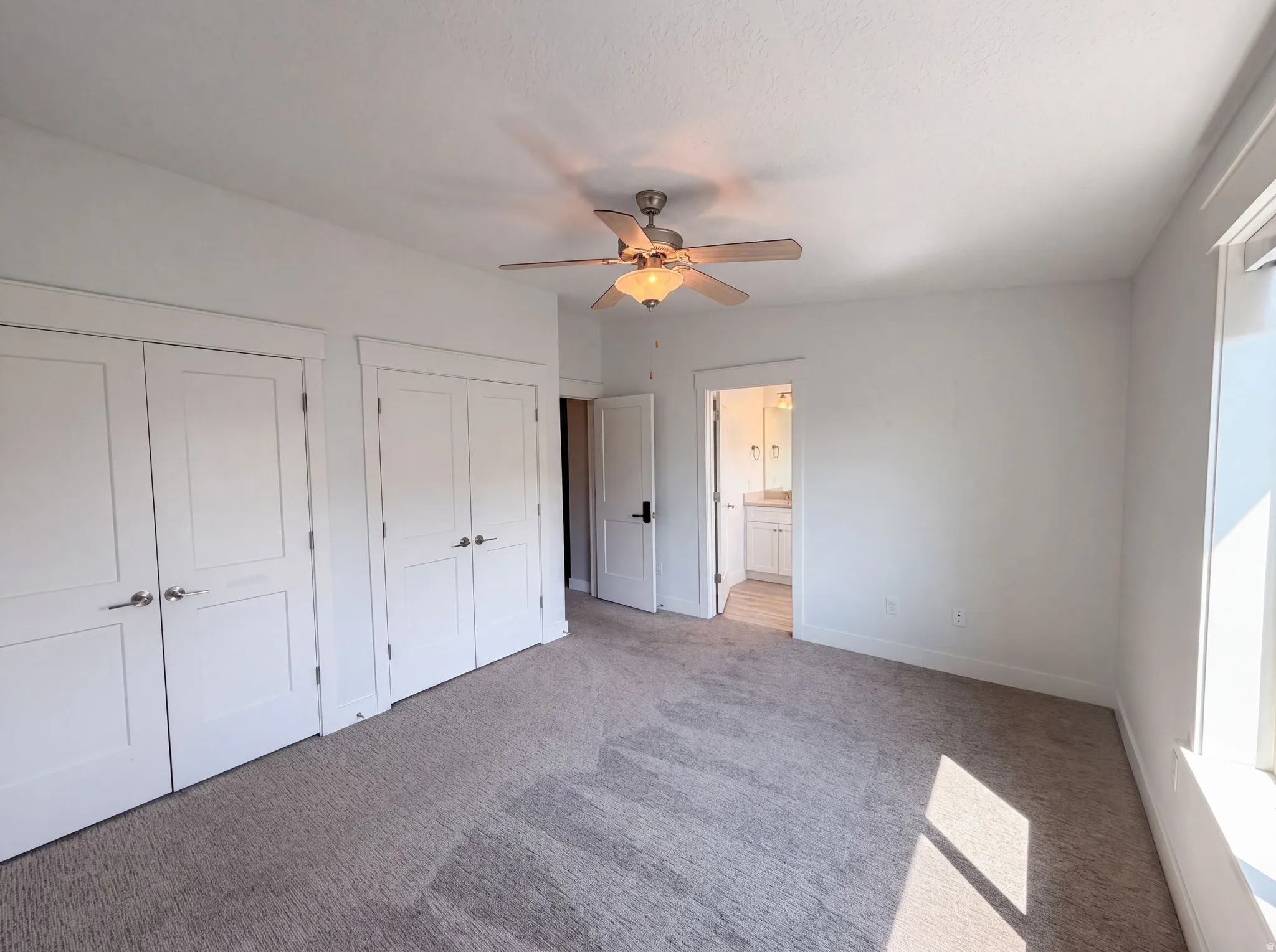 Recessed panel closet doors, ceiling fan with integrated lighting, window with white trim, and light gray carpeting