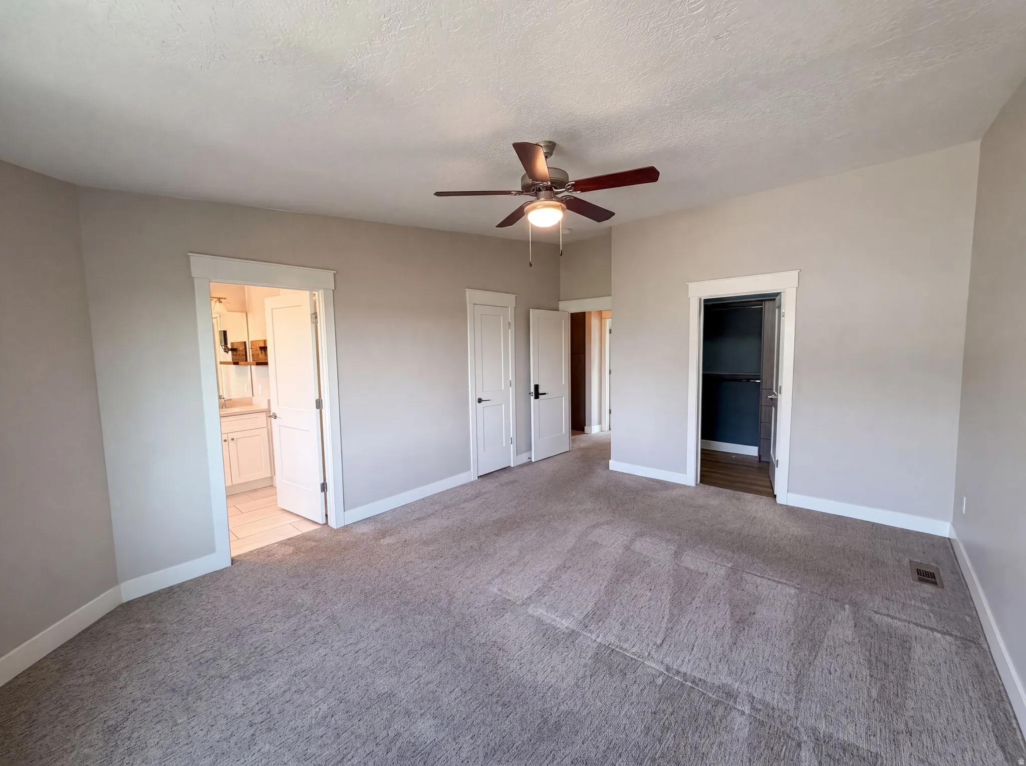 Spacious room with neutral carpet, light-toned walls, and a ceiling fan with integrated lighting