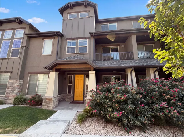 Multi-level exterior with a stone and stucco finish, featuring a covered entry, an elevated balcony, and architectural window details