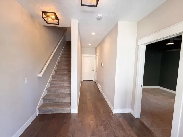 Wood-finish flooring, staircase with carpeted treads, contemporary flush-mount lighting, recessed lighting, and crisp white trim