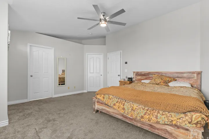 Plush carpet flooring, multiple panel doors, and a ceiling fan with integrated lighting