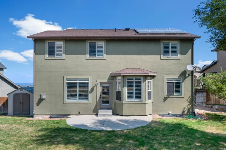 Stucco exterior with multiple windows, a bay window feature, and solar panels on the roof