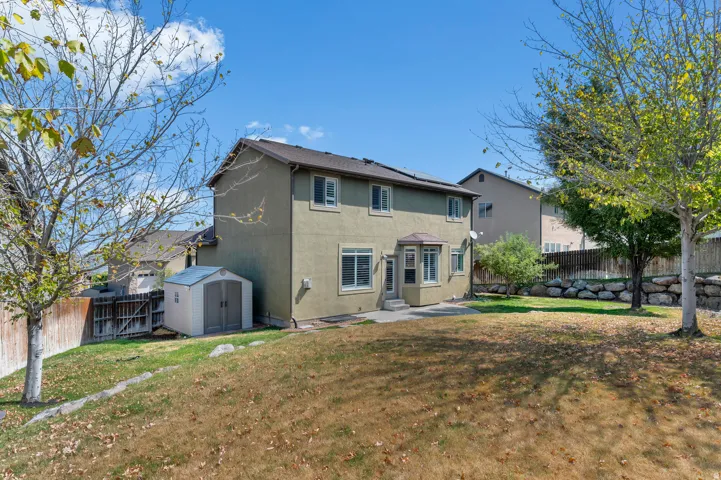 Rear stucco exterior with multiple windows, a bay window feature, and a concrete patio