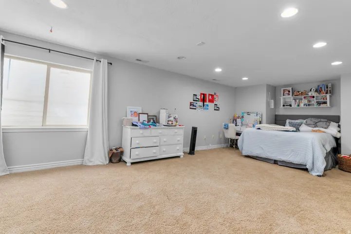 Wall-to-wall carpeting with recessed lighting, a window with curtains, and a built-in shelf unit
