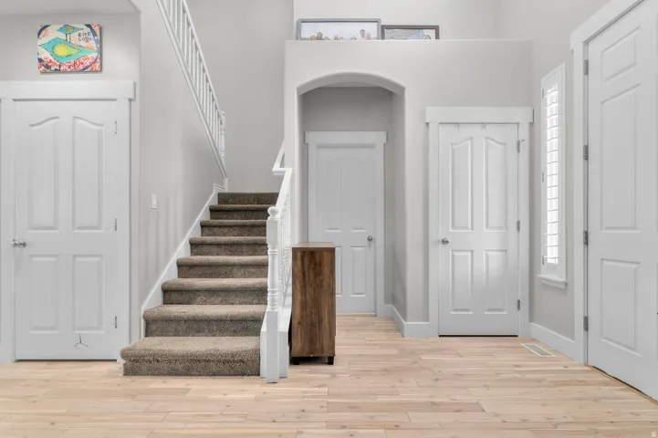 Hardwood flooring with a carpeted staircase featuring a white railing