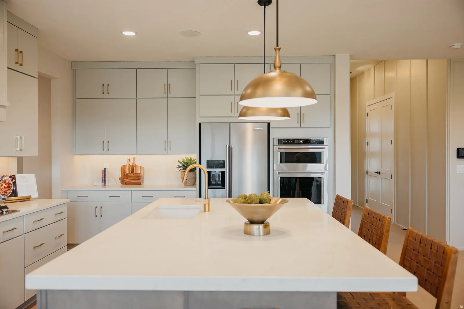 Kitchen featuring light-toned cabinetry, stainless steel appliances, a large center island with an integrated sink, and pendant lighting