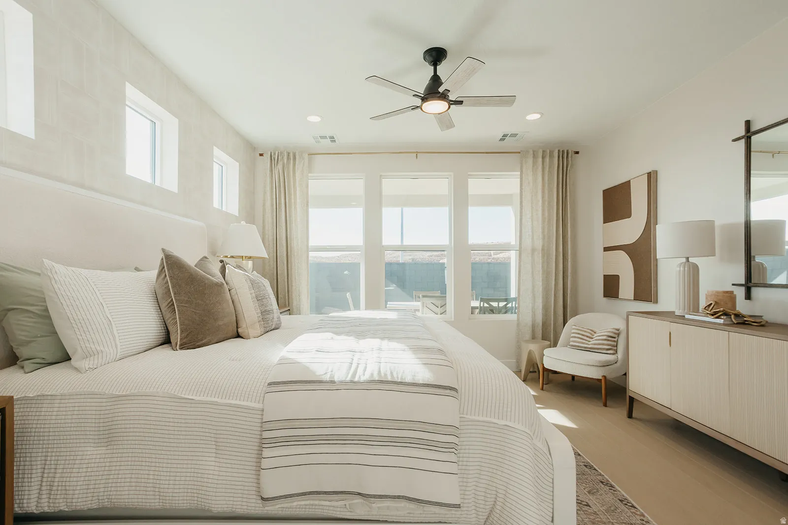 Recessed lighting, ceiling fan with light fixture, multiple windows, light wood-finish flooring, and a built-in window bench