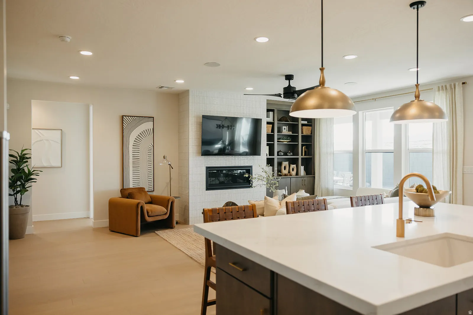 Contemporary living area featuring wood-finish flooring, a fireplace with tile surround, built-in shelving, recessed lighting, and large windows
