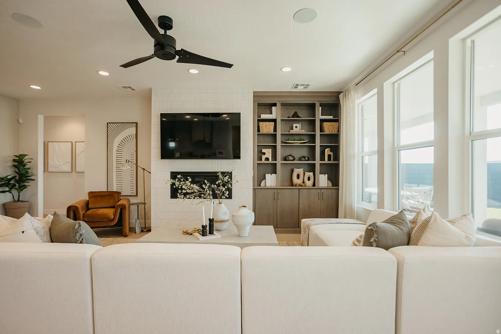 Living area featuring a ceiling fan, recessed lighting, and a built-in media center with shelving
