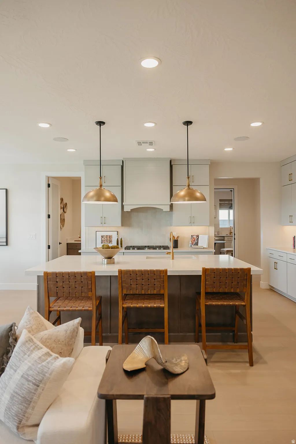 Spacious kitchen island with a light-toned countertop, recessed ceiling lighting, and brass pendant fixtures