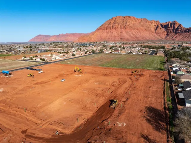 Expansive undeveloped land parcel with red earth, surrounded by a residential community and natural rock formations