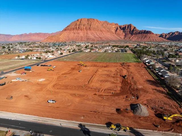Expansive lot with red earth grading, bordered by a paved road
