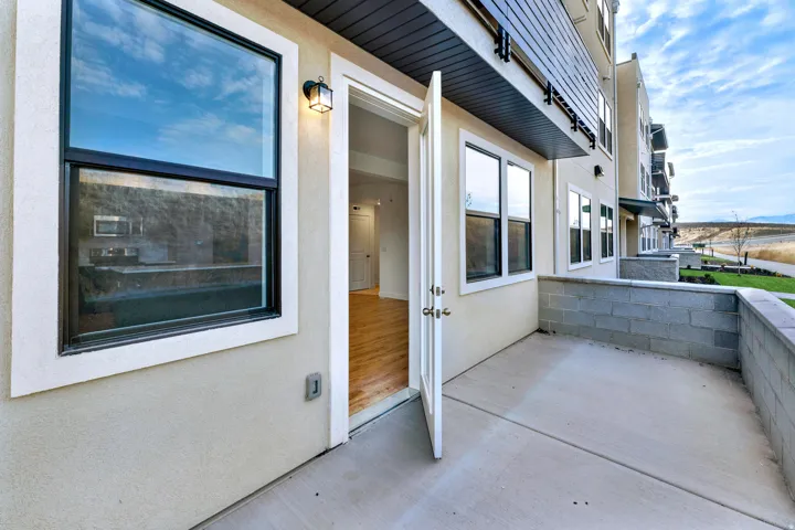 Private patio with concrete flooring, block retaining wall, and exterior lighting