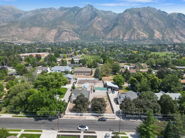 Mountain range backdrop, abundant mature trees, residential neighborhood setting, broad street frontage