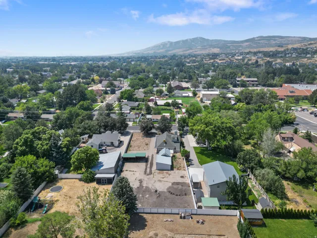 Expansive aerial perspective showcasing properties within a residential area, surrounded by abundant mature trees and distant mountain ranges