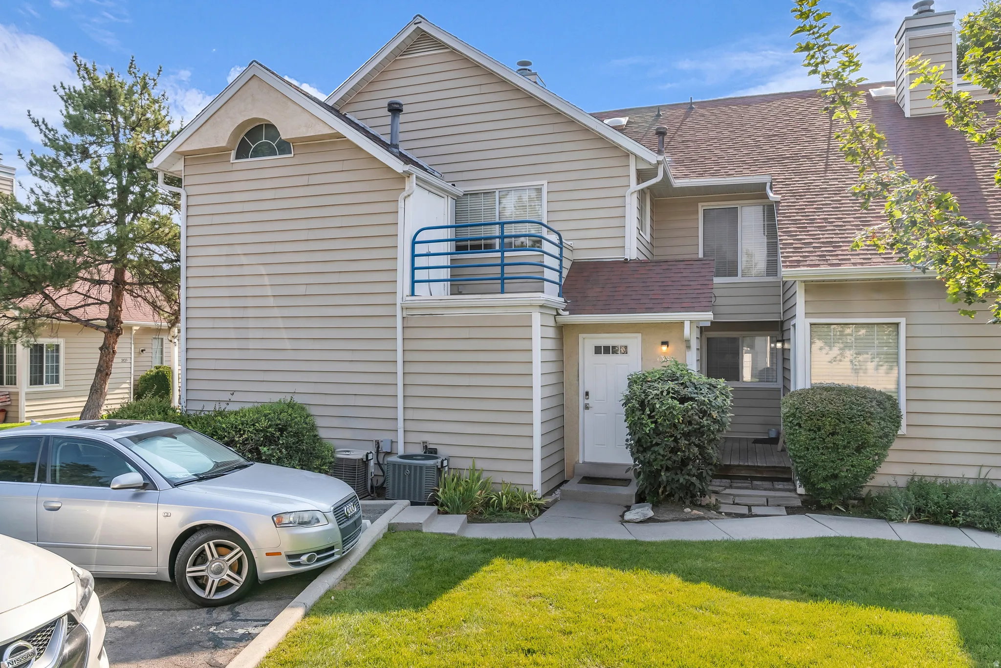 Horizontal siding exterior with a pitched shingle roof, arched window accent, and a balcony with blue railing