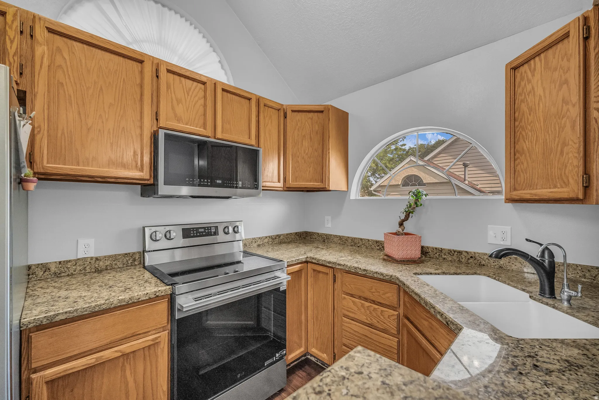 Wood-finish cabinetry paired with speckled stone countertops and a stainless steel appliance suite