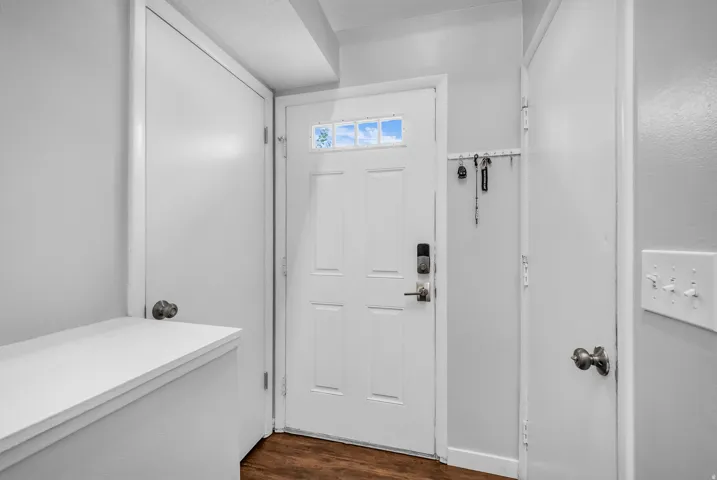 Bright entryway featuring a six-panel white entry door with transom window, white drywall construction, recessed lighting, and warm wood-finish flooring throughout