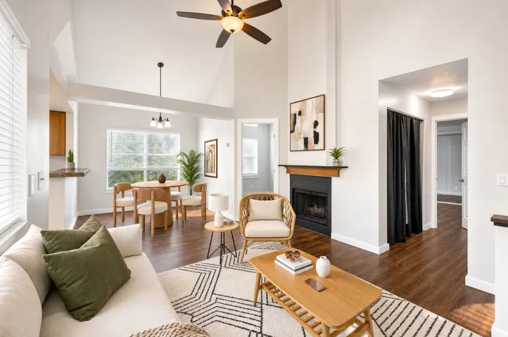 Vaulted ceilings with a ceiling fan, a fireplace with a wood mantel, wood-finish flooring, a breakfast bar, and a dining area with a chandelier